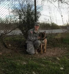 A picture of Melany in Army uniform with a dog